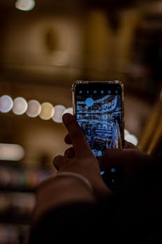 A person's hand using a smartphone camera to capture a shopping mall's interior.
